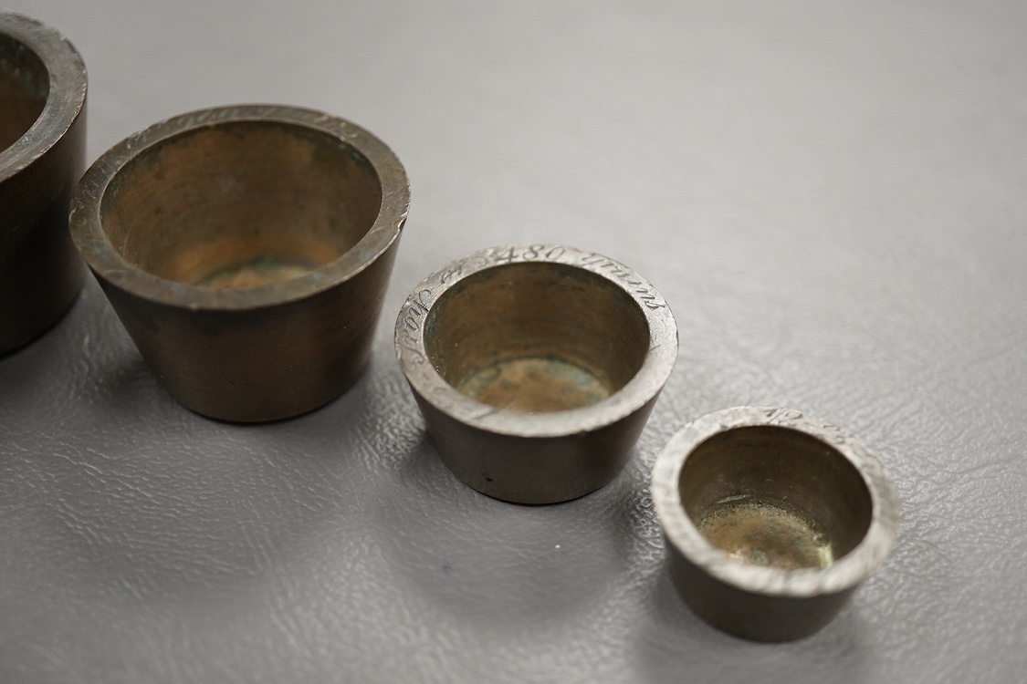 Two sets of bronze Troy nesting weights, one incomplete, with engraved rims, largest 8oz